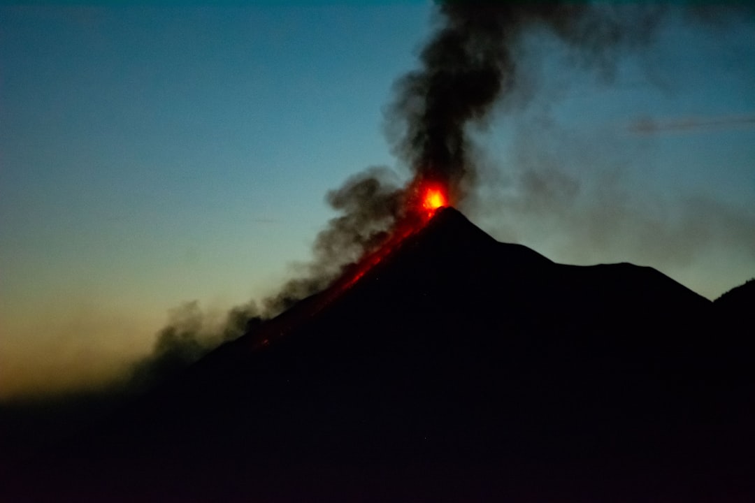 a volcano erupts smoke as the sun sets
