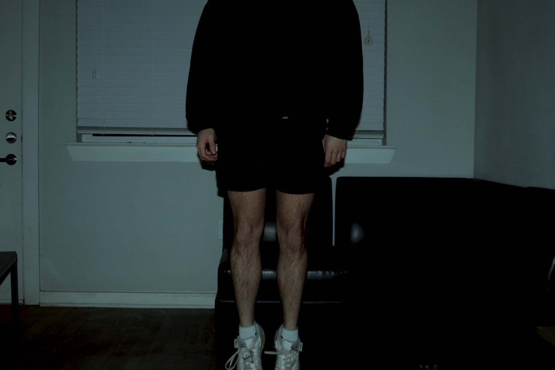 a man standing in a dark room wearing white shoes