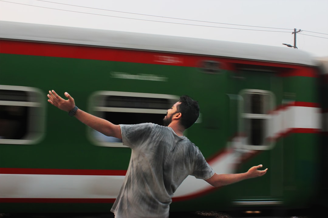 A man standing in front of a green and red train