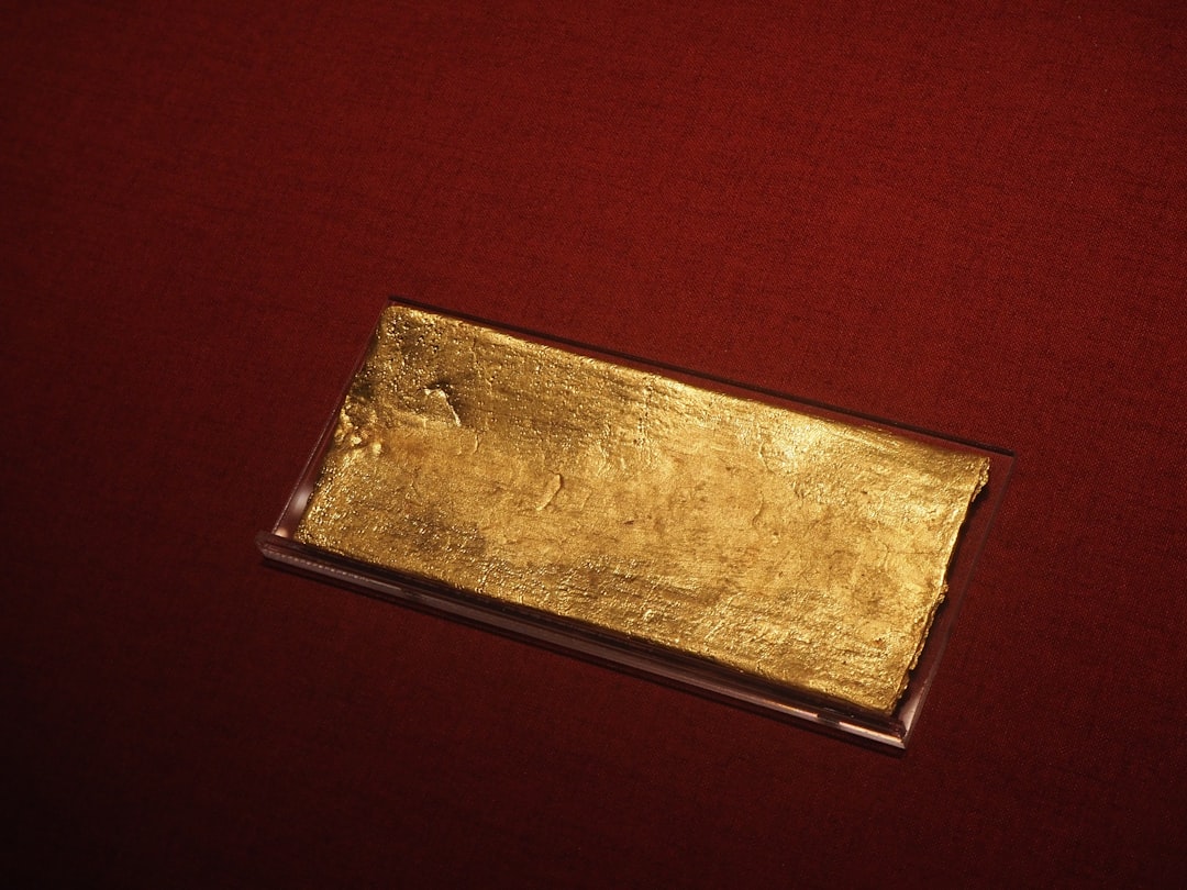 A gold bar rests on a red surface