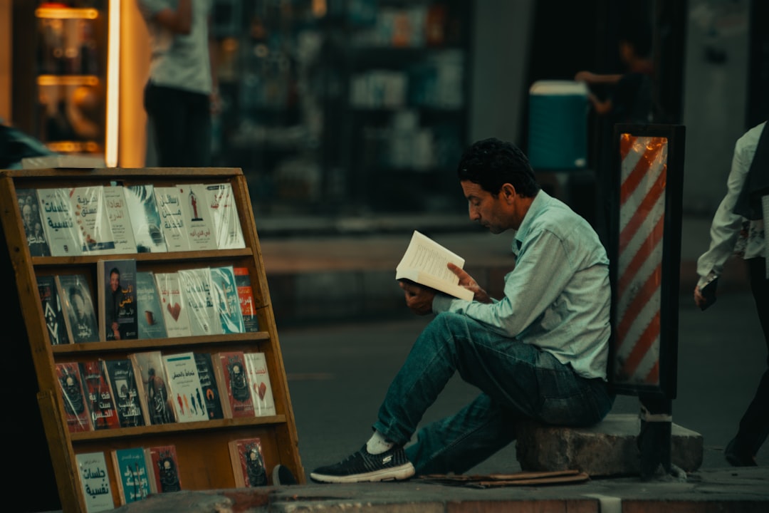 Man reads book beside street display of books