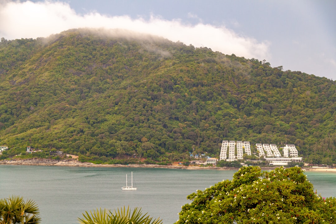 Sailboat on the water with lush green hills behind.